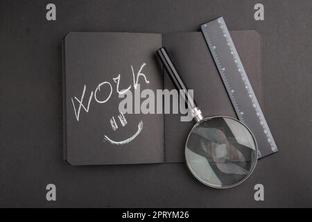 top view work written on black notebook lupa ruler on dark background Stock Photo