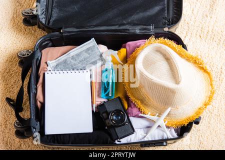 Open suitcase with traveler belongings clothes and accessories of things ready packing to be taken on summer holiday, Travel vacation luggage preparat Stock Photo