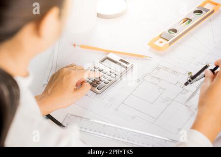 Architectural project workplace. Engineer sketching construction project, Architect drawing with divider compass on house plan blueprint paper for rep Stock Photo