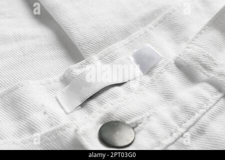 Blank clothing label on white jeans, closeup Stock Photo
