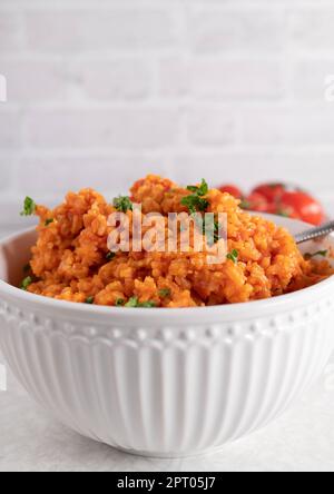 Greek tomato brown rice in a white bowl isolated on light background Stock Photo