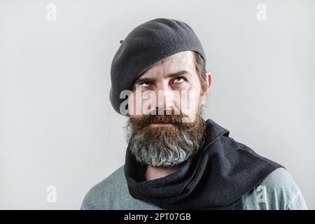 Bearded man in gray beret with scarf. Studio portrait on a light background. Stock Photo