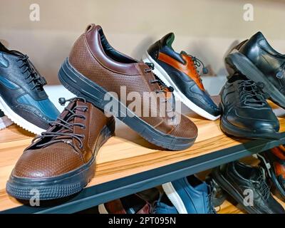 Handcrafted brown leather men shoes on the display shelves in the shoe shop. Stock Photo