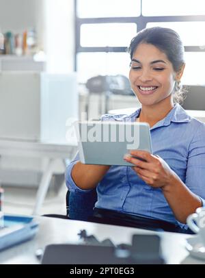 Positivity leads to productivity. a young businesswoman using a digital tablet at work Stock Photo