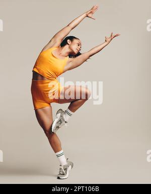 Flexible female athlete performing a gymnastics workout, balancing on one leg. Woman with a fit body and toned physique demonstrates her agility and s Stock Photo