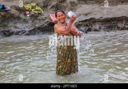 Burmese woman bathing & washing during Southeast Asia heatwave, life along the Irrawaddy River, heat wave records, largest waterway in Myanmar (Burma) Stock Photo