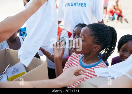 Excited to see all her new clothes. volunteer workers handing out clothing to underprivileged children Stock Photo