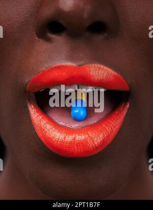 Ready for a rush. Cropped view of an african woman with bright red lips taking a pill Stock Photo