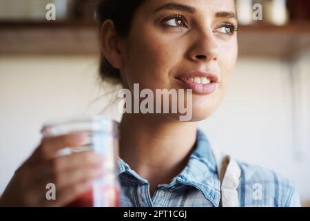 The juice was definitely worth the squeeze. A beautiful young woman standing indoors and drinking freshly-juiced juice Stock Photo