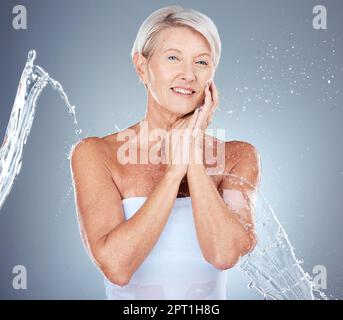 Skincare, water splash and portrait of senior woman in studio for wellness, healthy skin and hydration. Beauty, spa and old woman with water stream fo Stock Photo