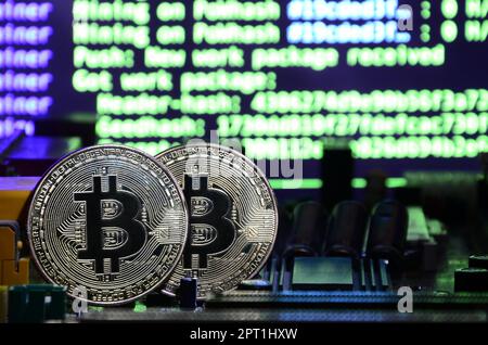 The digital process of cryptocurrency mining by using the GPUs. Bitcoins and video card on a working display and mining screen Stock Photo