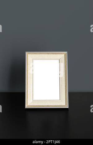 Vertical frame Mockup standing on wooden table in office room interior on dark gray wall background Stock Photo