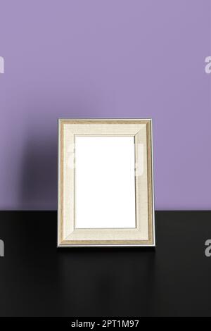Vertical frame Mockup standing on wooden table in office room interior on purple wall background Stock Photo