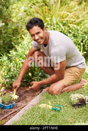 When the green-fingers kick in. Portrait of a young man gardening in his yard Stock Photo