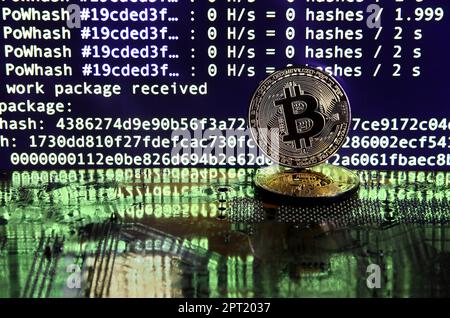 The digital process of cryptocurrency mining by using the GPUs. Bitcoins and video card on a working display and mining screen Stock Photo