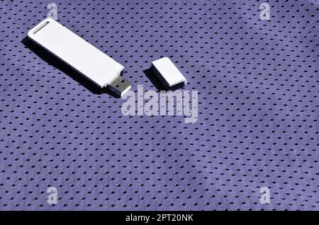 A modern portable USB wi-fi adapter is placed on the violet sportswear made of polyester nylon fiber Stock Photo