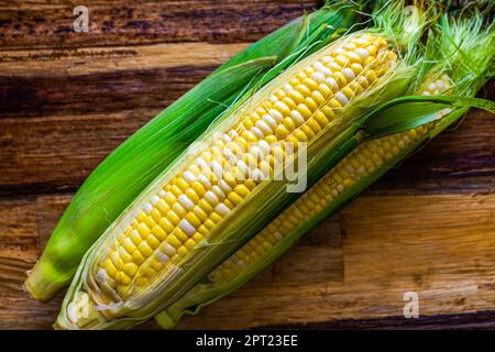 Fresh corn on the cob with husk. Above, close up. Stock Photo