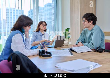 College students with teacher sitting at desk in classroom studying languages, sciences Stock Photo