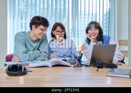 College students with teacher sitting at desk in classroom studying languages, sciences Stock Photo