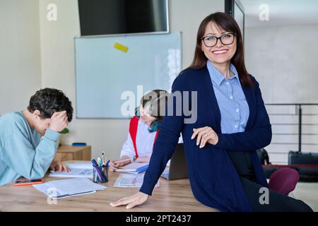 Portrait of middle aged female teacher, looking at camera, in classroom Stock Photo