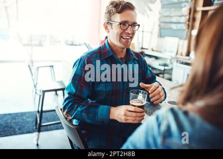 Interesting conversation with interesting people. a happy young man and woman having beers at a bar. Stock Photo