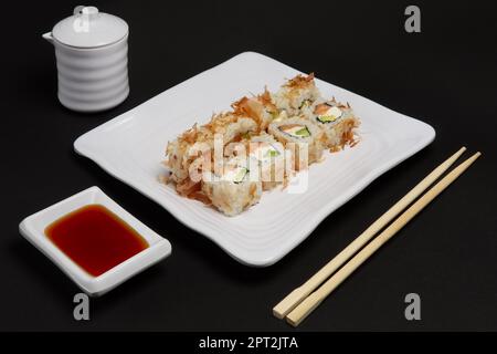 Portion of bonito rolls served on plate with soy sauce and wooden hashi. Stock Photo