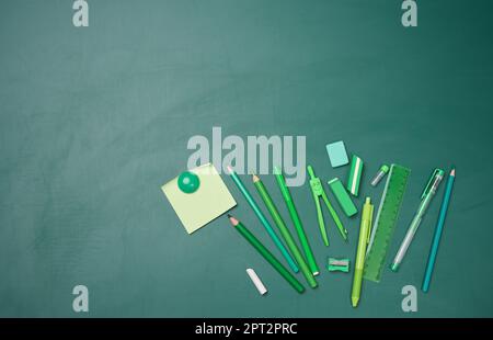 School supplies on empty green chalk board, top view. Back to school Stock Photo