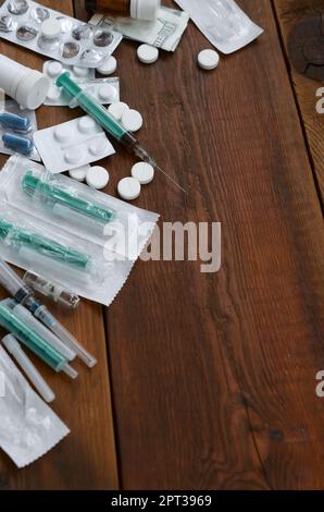 Narcotic stuff with many pills and syringes lies on wooden table and ready to use. Synthetic drug addiction concept. Hazardous medical substances Stock Photo