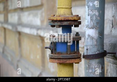 Yellow gas pipe in front of residential building wall. Stone wall texture background natural color. Stock Photo