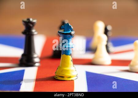 A chess king with a painted flag of Ukraine stands on the flags of great britain, friendship Stock Photo