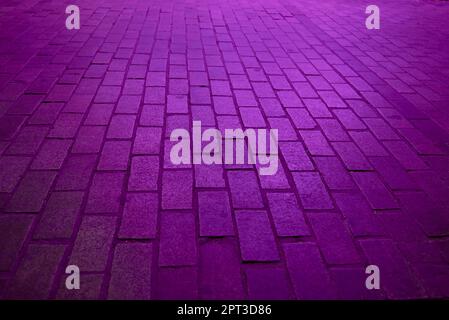 Background. Rectangular cobblestone street with purple light.No one, parallel, perpendicular, perspective depth Stock Photo
