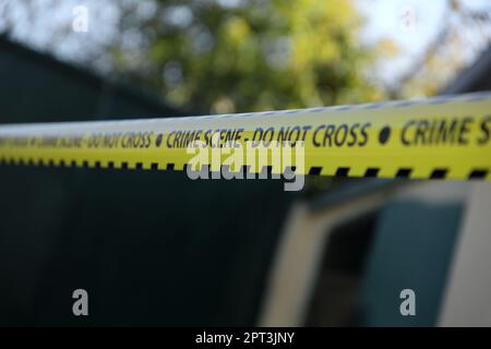 Crime scene tape for covering the area cordon. Yellow tape with blurred forensic law enforcement background in cinematic tone and copy space Stock Photo