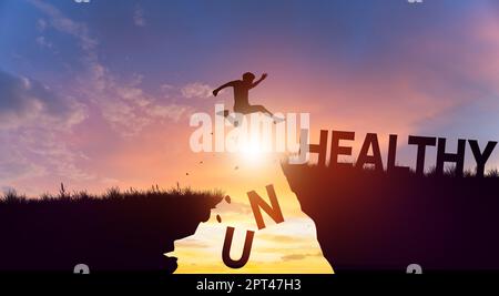 Silhouette man jumping over cliffs mountain with cloud sky and sunrise. Health and Unhealthy Concept. Stock Photo