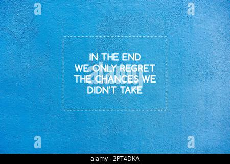 Inspiring motivation quote on blue wall - in the end we only regret the chances we didn't take Stock Photo