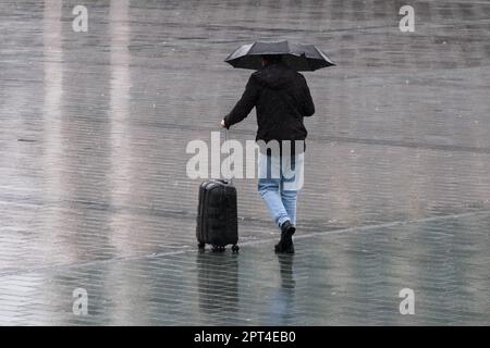 Close up man holding umbrella under rain and has suitcase walking back side and no face and reflection on ground. Rain holiday autumn concept. Stock Photo