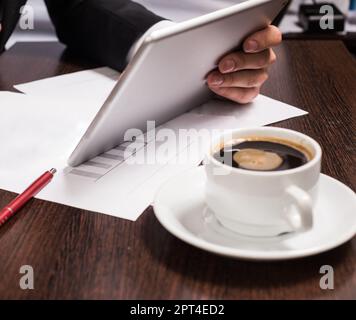 Businessman in business suit uses tablet. on the table Cup cafe, mobile, pen. Stock Photo