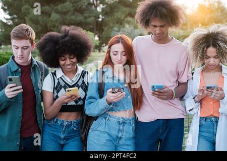 Group of students outdoors all looking at their smartphone and forgetting to socialize. Concept: technology, unsociable, disconnection Stock Photo