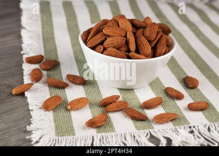 A bowl of almonds on the table. Scattering of almonds. Healthy snack with nuts. Stock Photo