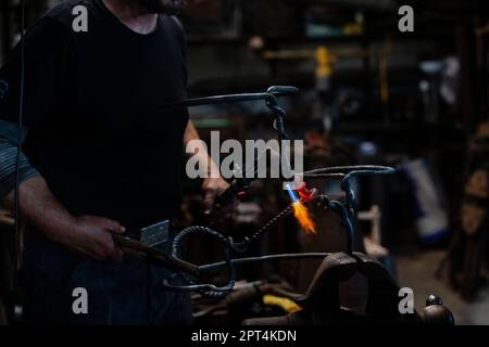 Blacksmith working in workshop on the vice with hot metals with anvile and flame forger Stock Photo