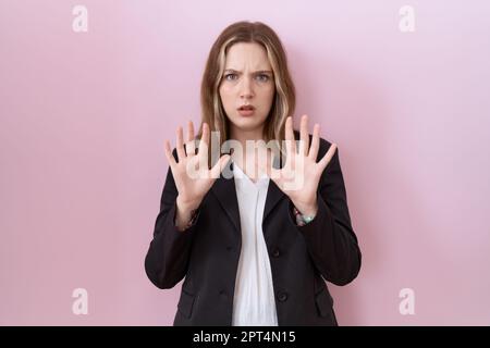 Young caucasian business woman wearing black jacket moving away hands palms showing refusal and denial with afraid and disgusting expression. stop and Stock Photo
