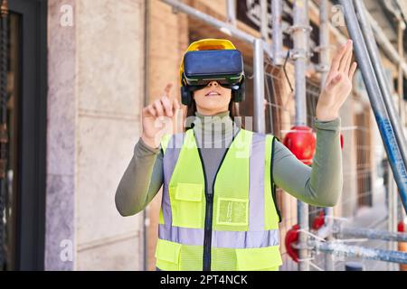 Young beautiful hispanic woman architect using virtual reality glasses at street Stock Photo