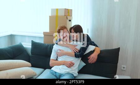 Camera moving back from young joyful couple of new owners of the apartment. Slow motion. Happy excited family bought new house. Moving day. Mortgage Stock Photo