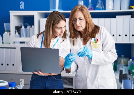 Mother and daughter scientists using laptop working at laboratory Stock Photo