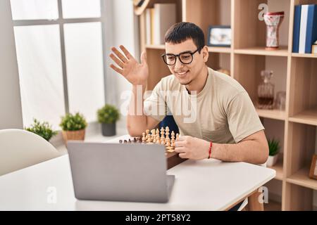 Young arab man playing chess online celebrating achievement with happy smile and winner expression with raised hand Stock Photo