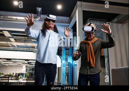 Creepy zombie employees working using virtual reality futuristic technology VR headset at office Stock Photo