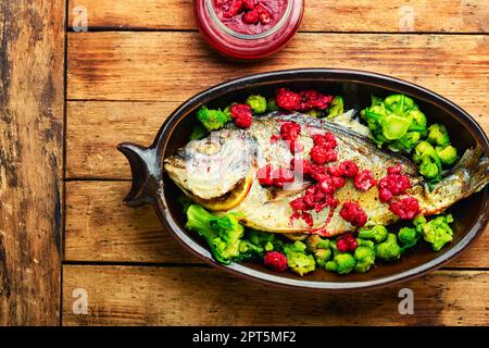 Appetizing grilled fish in fruit marinade. Seafood on old wooden table Stock Photo