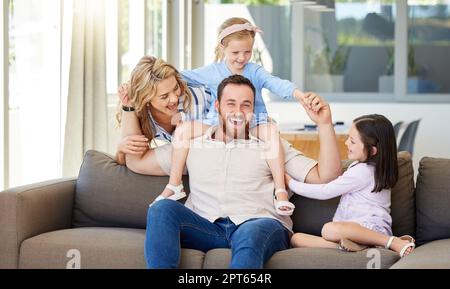Carefree caucasian family playing in the living room at home. Active little girls spending time with loving parents. Happy kids bonding with mom and d Stock Photo