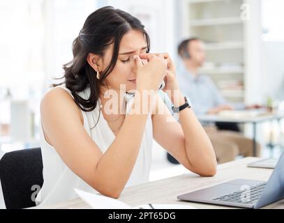 Im struggling hard today. a young businesswoman looking stressed out while talking on a cellphone in an office Stock Photo