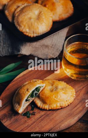 Freshly Baked Hand Pies Filled with Blue Chives and Mushrooms with Cup of Green Tea. And Sliced One Pie Stock Photo