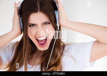 I cant hear you over the sound of this craziness. a young woman listening to music against a studio background Stock Photo